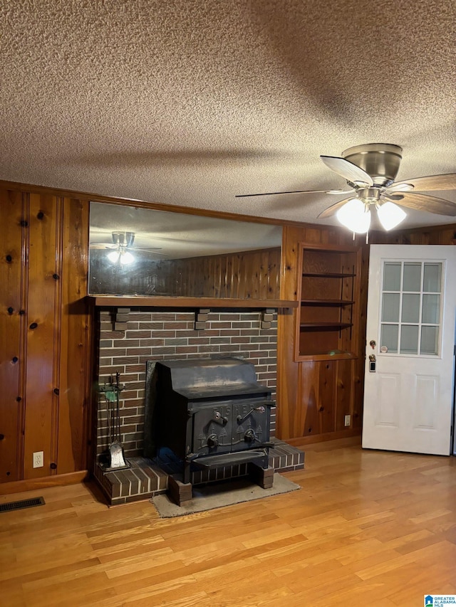 details with a textured ceiling, hardwood / wood-style flooring, a wood stove, and wooden walls