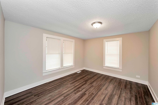 unfurnished room with a textured ceiling, dark hardwood / wood-style flooring, and a healthy amount of sunlight