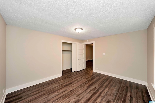 unfurnished bedroom with a textured ceiling, a closet, and dark wood-type flooring