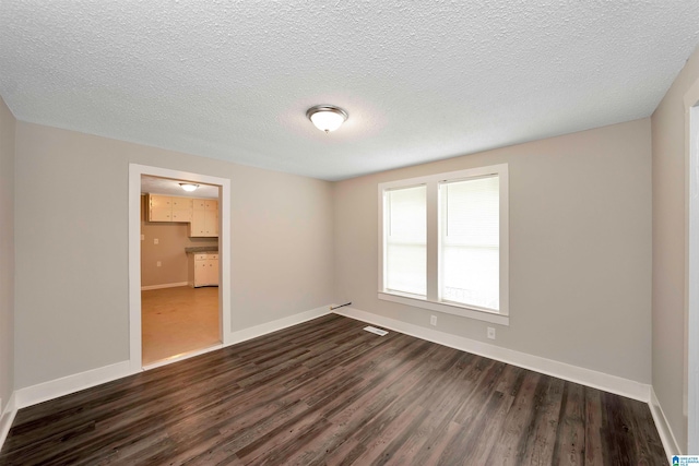 empty room with a textured ceiling and dark wood-type flooring