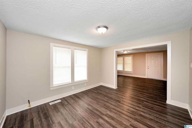 empty room featuring dark hardwood / wood-style flooring and a textured ceiling