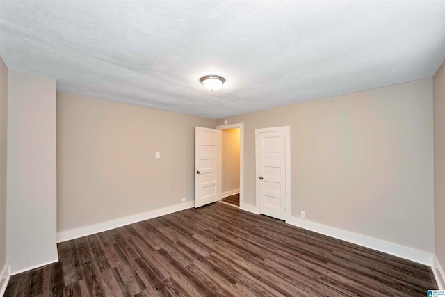 spare room with a textured ceiling and dark hardwood / wood-style floors