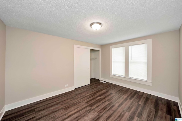 unfurnished bedroom with dark hardwood / wood-style flooring, a textured ceiling, and a closet