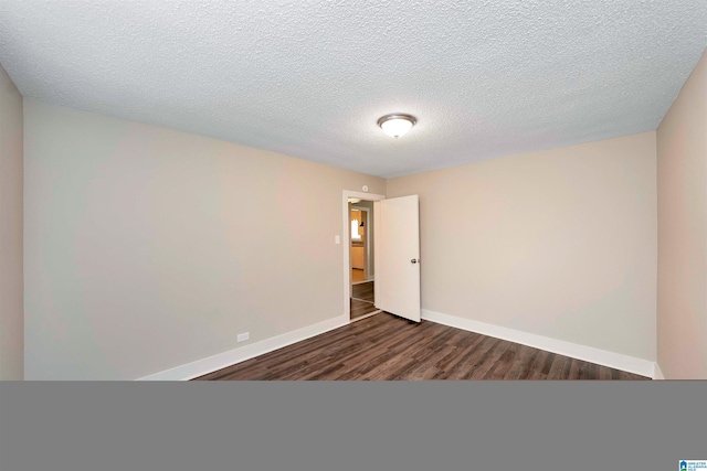 empty room featuring a textured ceiling and dark hardwood / wood-style floors