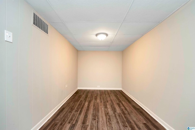 spare room featuring dark hardwood / wood-style flooring and a paneled ceiling