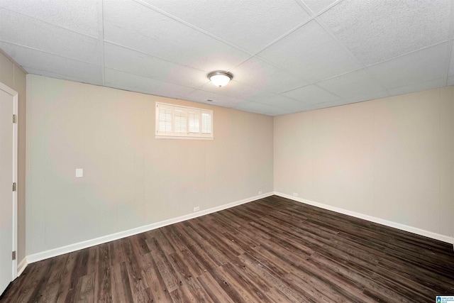 basement featuring a paneled ceiling and dark wood-type flooring