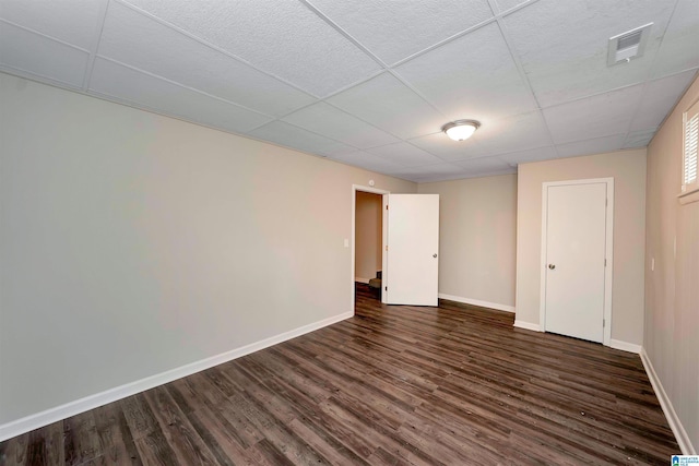 empty room featuring dark hardwood / wood-style flooring and a drop ceiling