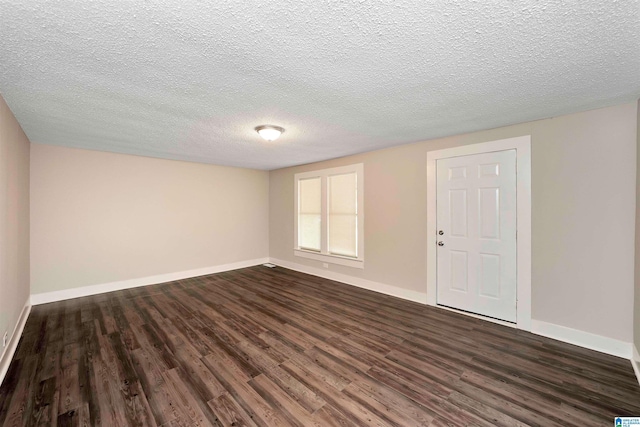 spare room featuring a textured ceiling and dark wood-type flooring