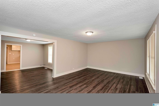 unfurnished room with a textured ceiling and dark wood-type flooring