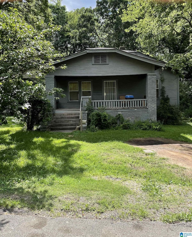 bungalow-style home featuring covered porch and a front lawn