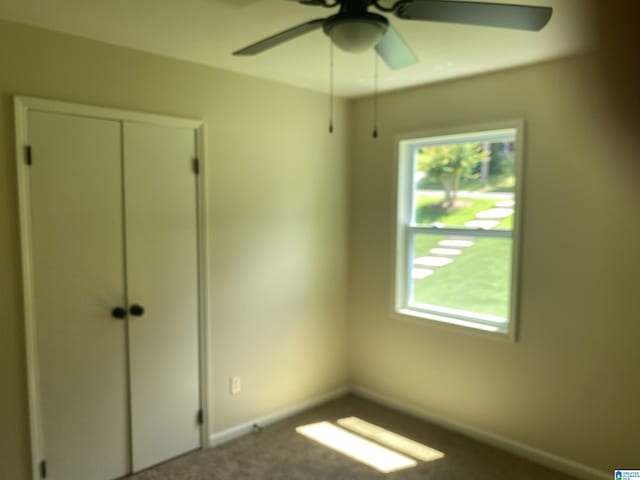 unfurnished bedroom with ceiling fan, a closet, carpet, and multiple windows