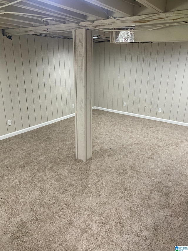 basement featuring carpet flooring and wood walls