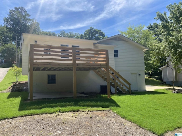 rear view of property featuring a wooden deck, a patio area, and a lawn