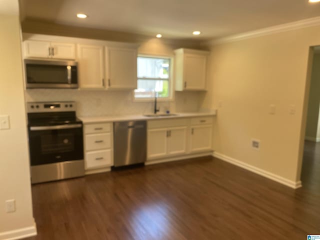 kitchen with sink, crown molding, dark wood-type flooring, appliances with stainless steel finishes, and white cabinetry