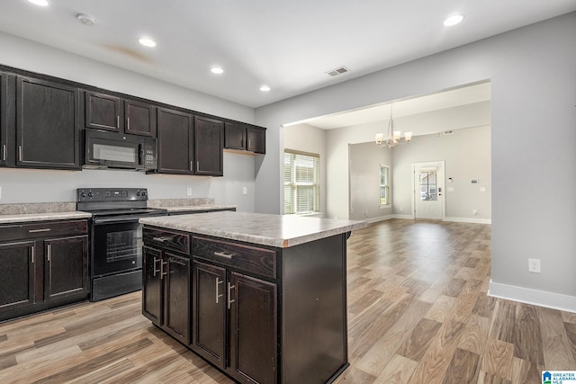 kitchen with dark brown cabinets, a kitchen island, black appliances, and light wood-type flooring