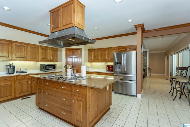 kitchen featuring light stone countertops, appliances with stainless steel finishes, ornamental molding, island range hood, and a center island