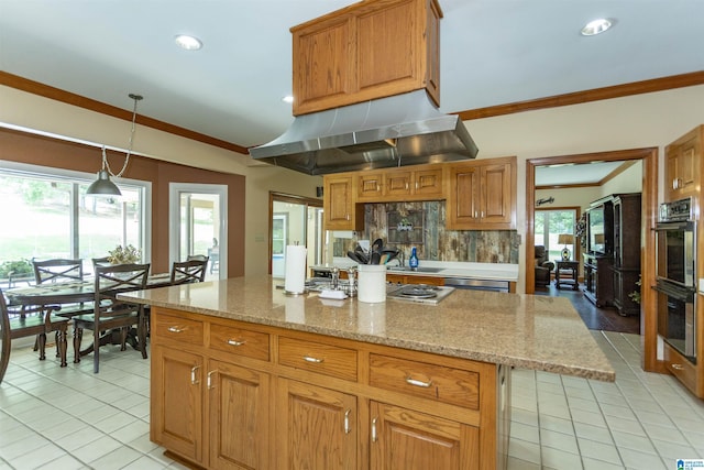 kitchen featuring appliances with stainless steel finishes, decorative light fixtures, a center island, plenty of natural light, and range hood