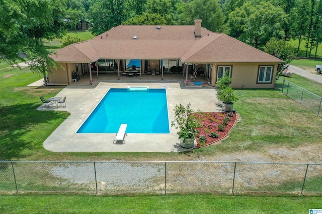 view of swimming pool with a patio area, a diving board, and a yard