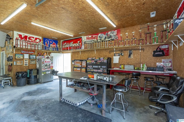 garage with a workshop area and stainless steel fridge