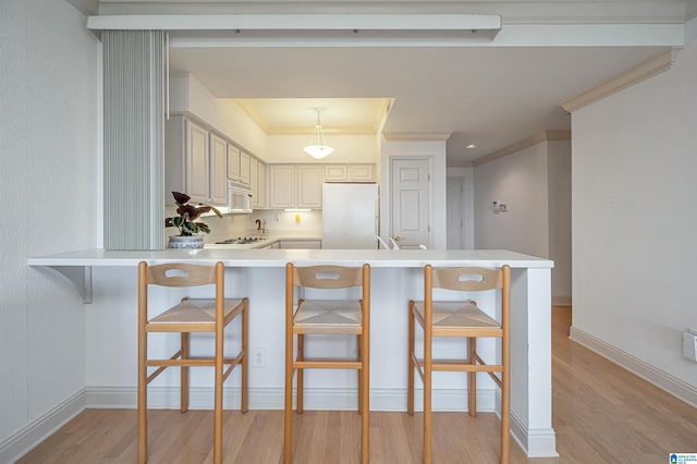 kitchen featuring white appliances, a peninsula, light countertops, and light wood finished floors