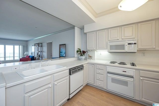kitchen with light wood-style flooring, a sink, white appliances, crown molding, and light countertops