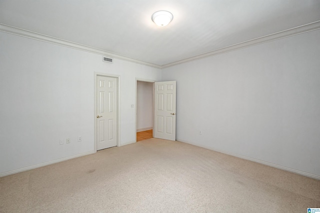 carpeted spare room with visible vents, baseboards, and ornamental molding