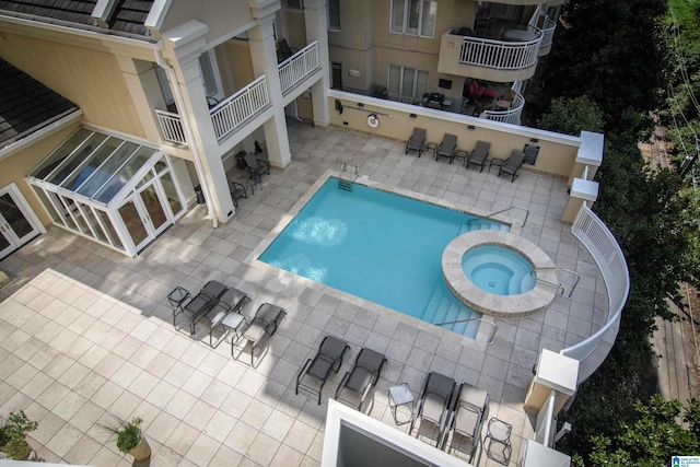 community pool with a patio area and a hot tub
