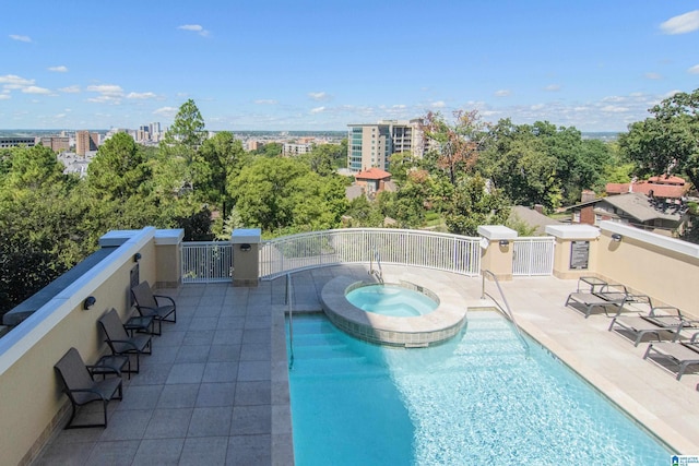 pool featuring a patio area, a city view, a hot tub, and fence