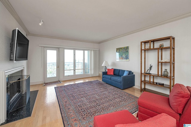 living room with crown molding, light wood-style flooring, a fireplace, and baseboards