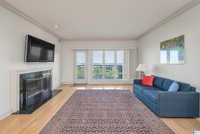 living room featuring a high end fireplace, crown molding, baseboards, and wood finished floors