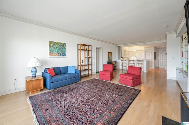 living area featuring crown molding, baseboards, and wood finished floors