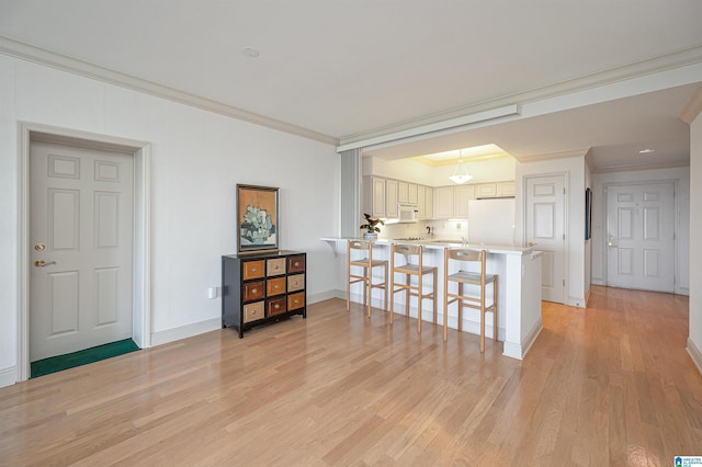 kitchen featuring ornamental molding, light wood-style flooring, a kitchen breakfast bar, white appliances, and a peninsula