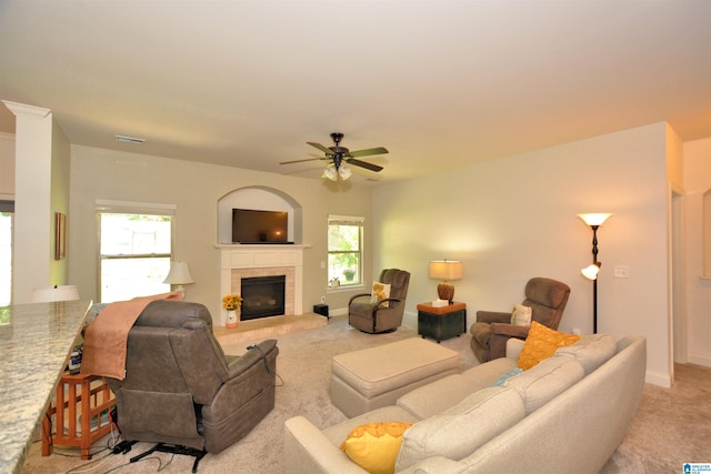 living room with ceiling fan, light colored carpet, a tile fireplace, and a wealth of natural light