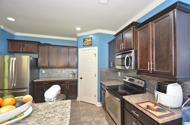 kitchen with appliances with stainless steel finishes, tasteful backsplash, light stone counters, crown molding, and dark brown cabinets