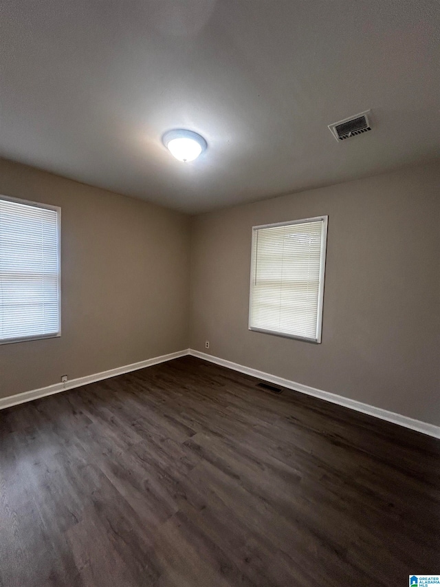 unfurnished room with plenty of natural light and dark hardwood / wood-style flooring