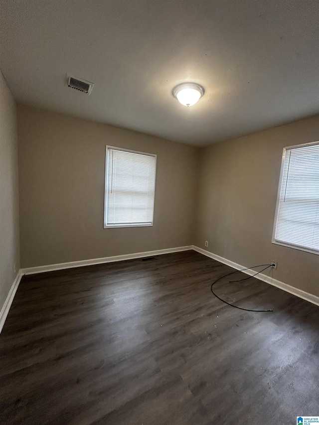 1616 Hatchet Ave, Tarrant, AL 35217 - empty room with dark wood finished floors, visible vents, and baseboards