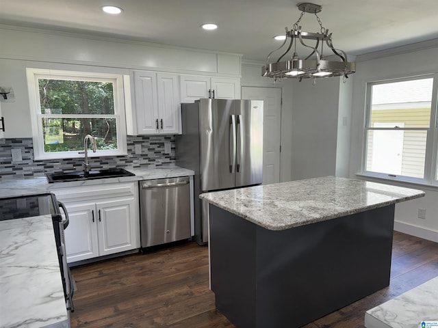 kitchen with pendant lighting, white cabinets, sink, a kitchen island, and stainless steel appliances