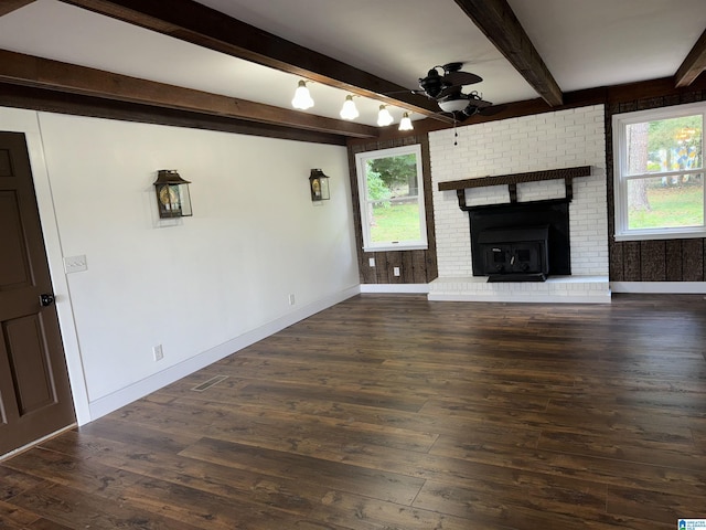 unfurnished living room featuring beamed ceiling, dark hardwood / wood-style floors, ceiling fan, and a fireplace