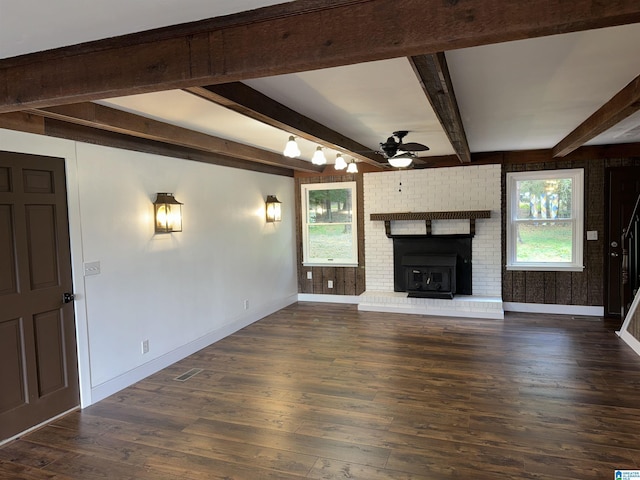 unfurnished living room featuring ceiling fan, a fireplace, beamed ceiling, and dark hardwood / wood-style floors