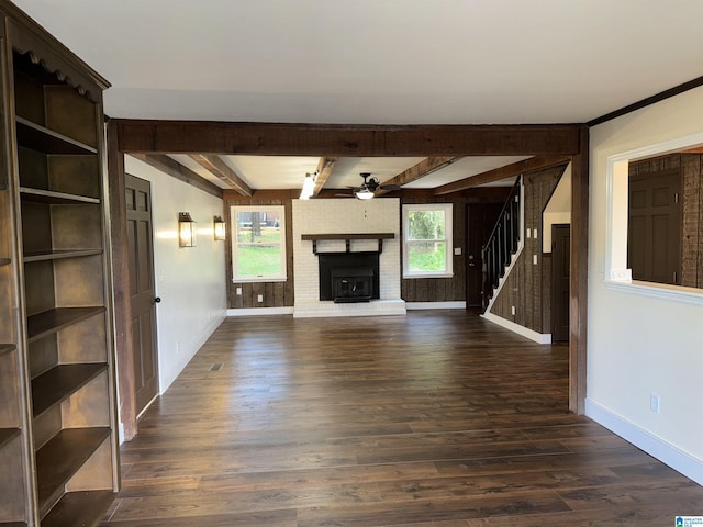 unfurnished living room with a fireplace, beam ceiling, dark hardwood / wood-style flooring, and ceiling fan