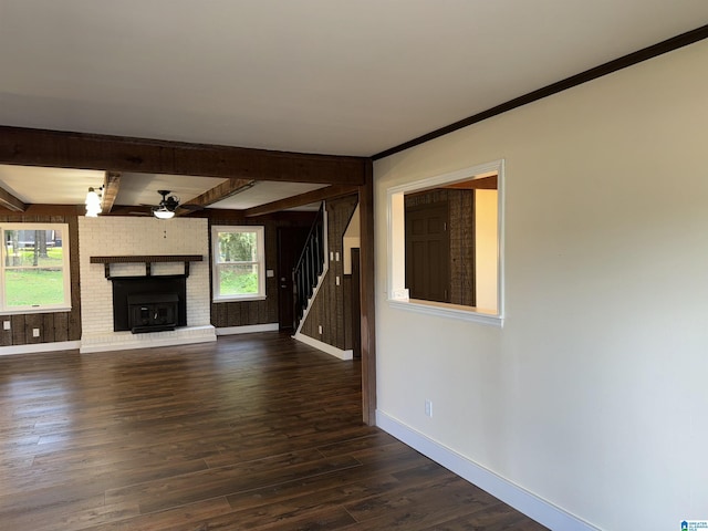 unfurnished living room with crown molding, ceiling fan, a fireplace, beam ceiling, and dark hardwood / wood-style flooring