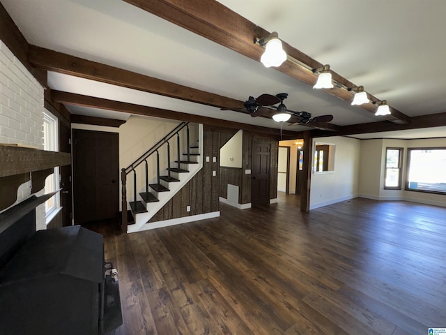 unfurnished living room with beam ceiling, dark hardwood / wood-style floors, and ceiling fan