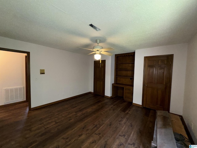 interior space featuring ceiling fan, dark hardwood / wood-style flooring, built in desk, and a textured ceiling