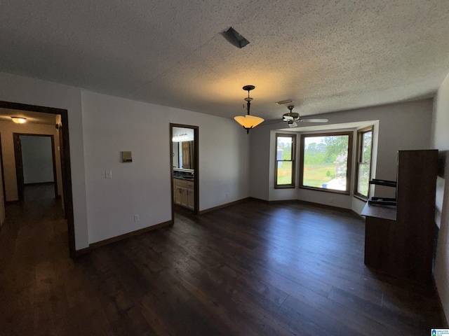 unfurnished living room featuring ceiling fan, dark hardwood / wood-style floors, and a textured ceiling