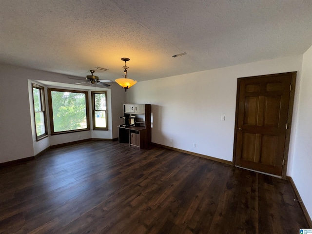 unfurnished living room with ceiling fan, dark hardwood / wood-style flooring, and a textured ceiling