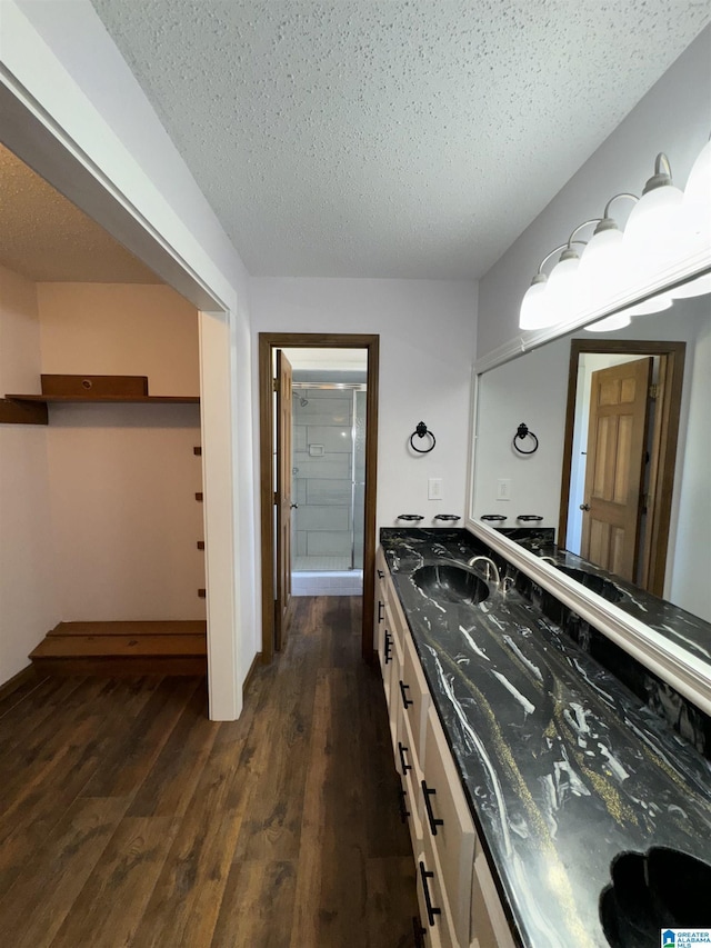 bathroom featuring vanity, wood-type flooring, a textured ceiling, and walk in shower