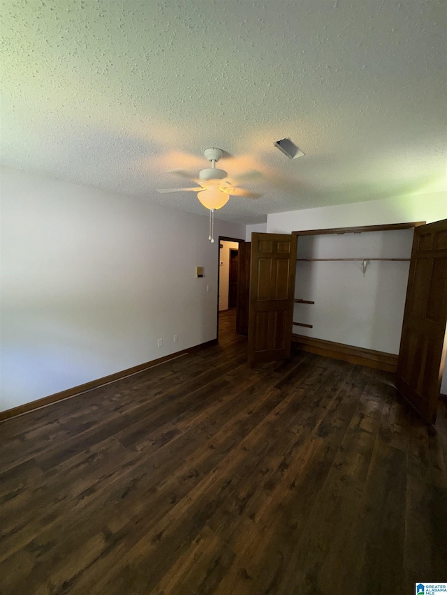 unfurnished bedroom with ceiling fan, dark hardwood / wood-style flooring, and a textured ceiling