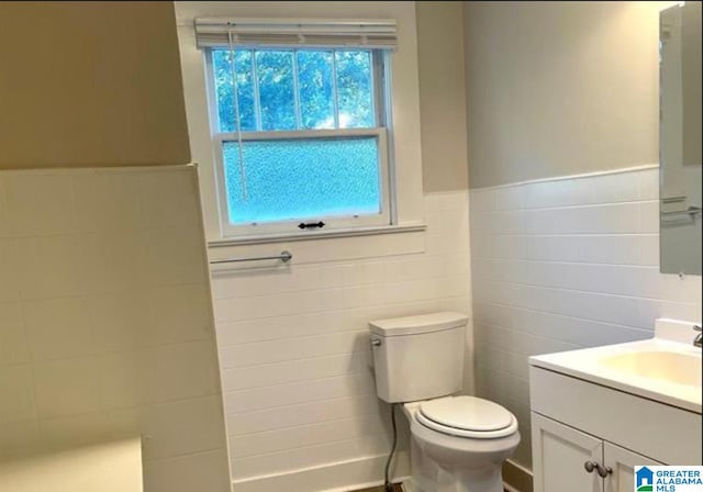 bathroom with vanity, tile walls, and toilet