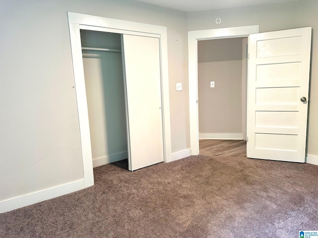 unfurnished bedroom with a closet and dark colored carpet