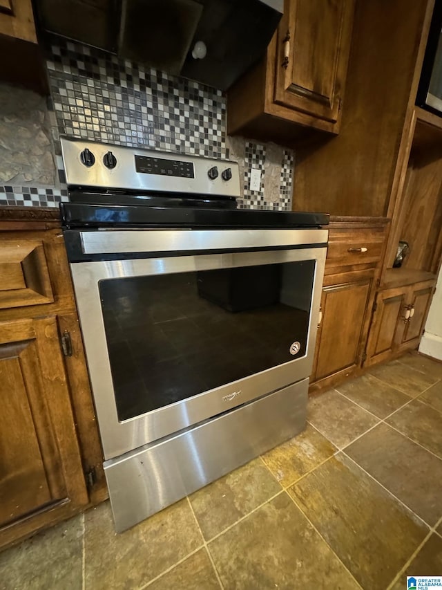 interior details with tasteful backsplash, wall chimney range hood, and stainless steel electric range